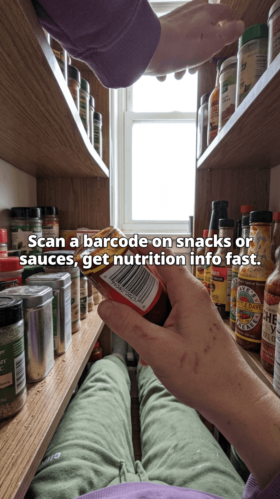 A first person view up into an open kitchen cupboard, one hand turning a jar to show its barcode among spice tins and hot sauce bottles, with a line of the post across the photo.