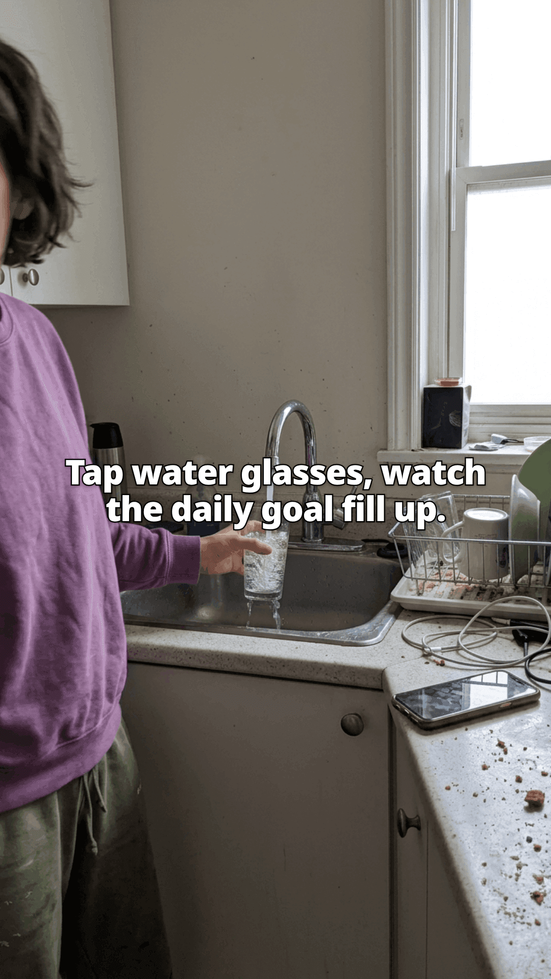 A woman filling a glass at a kitchen sink, a drying rack of dishes and her phone on the counter beside her, with a line of the post across the photo.